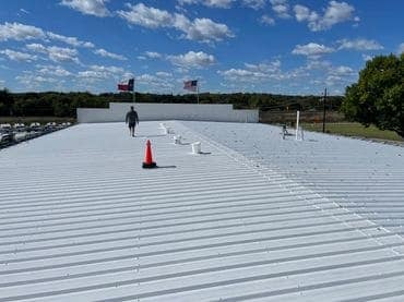 man walking across newly updated commercial business building with metal roof by collier roofing llc